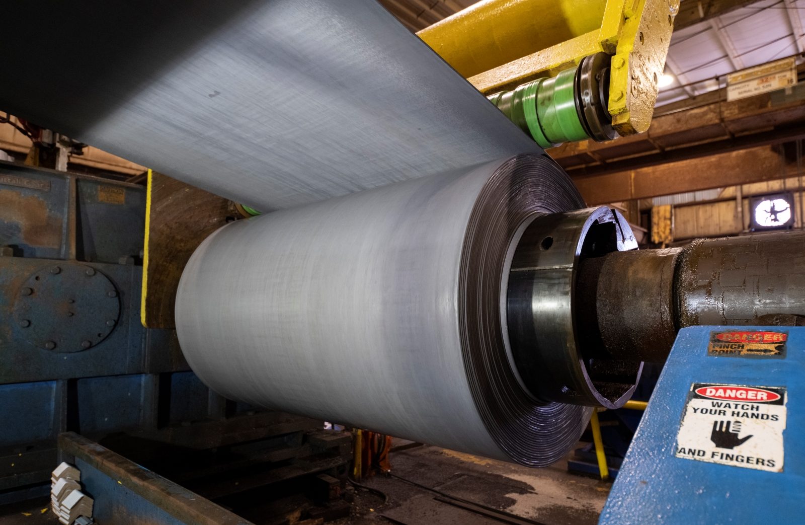 Close-up of a steel coil undergoing the pickling process on industrial machinery, highlighting the smooth surface finish.